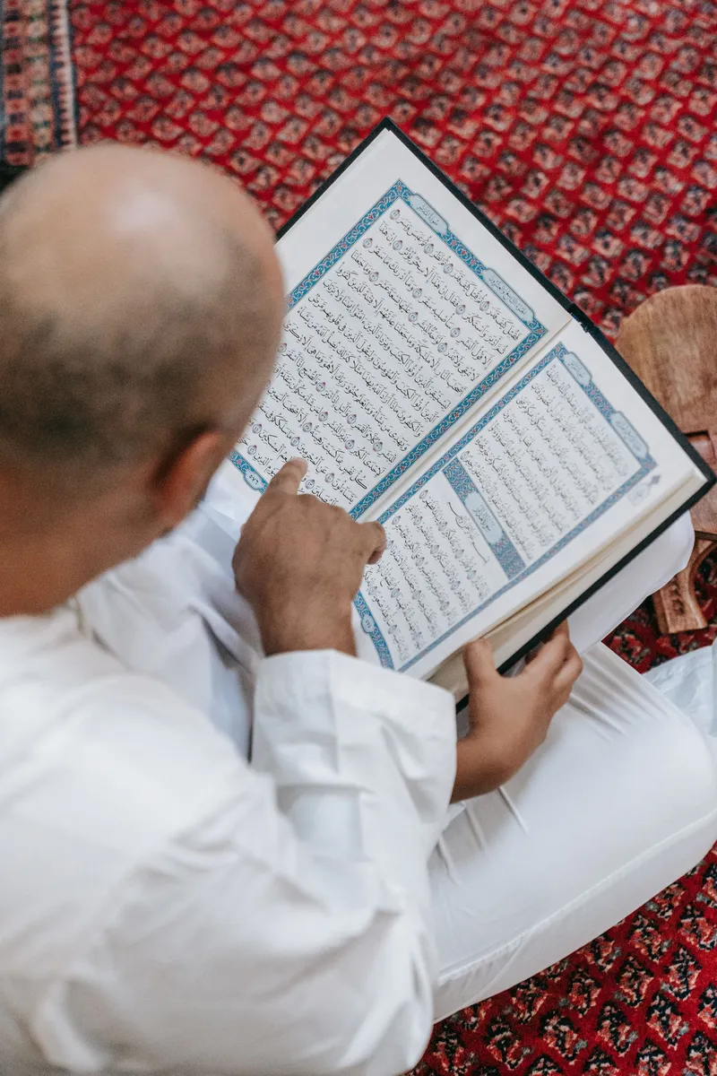 معلّم يتابع التلاوة بإصبعه على صفحة المصحف